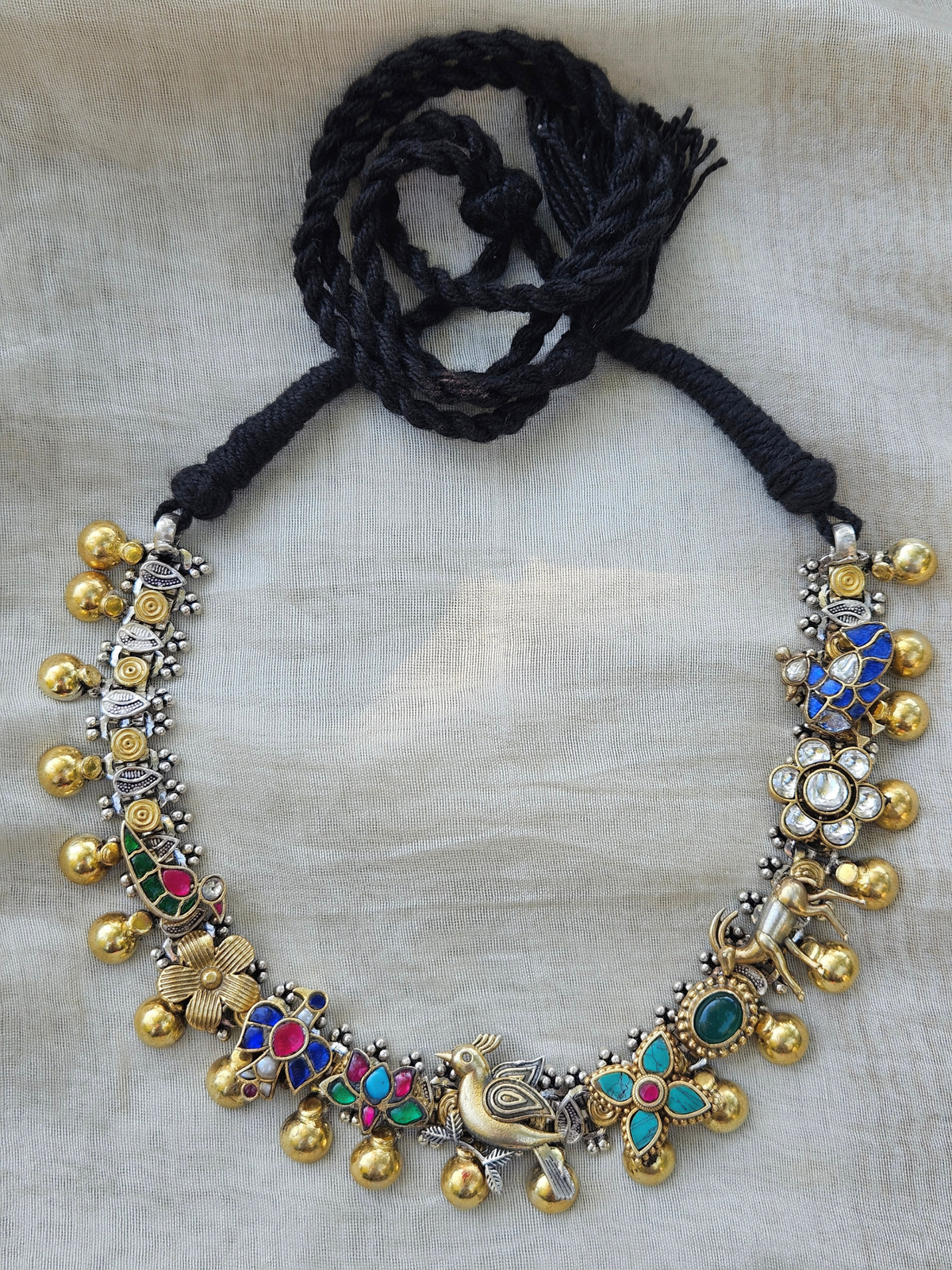 Dual-tone 925 sterling silver kundan charm necklace with parrot, fish, lotus, deer and bird motifs, gold drops and black thread tie, on ivory fabric