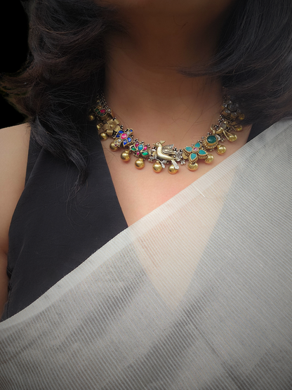 Woman wearing a dual-tone silver kundan charm necklace with a black blouse and an ivory handloom saree