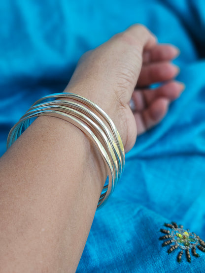 Thin silver bangles of 925 Sterling Silver  worn o hand in bright light
