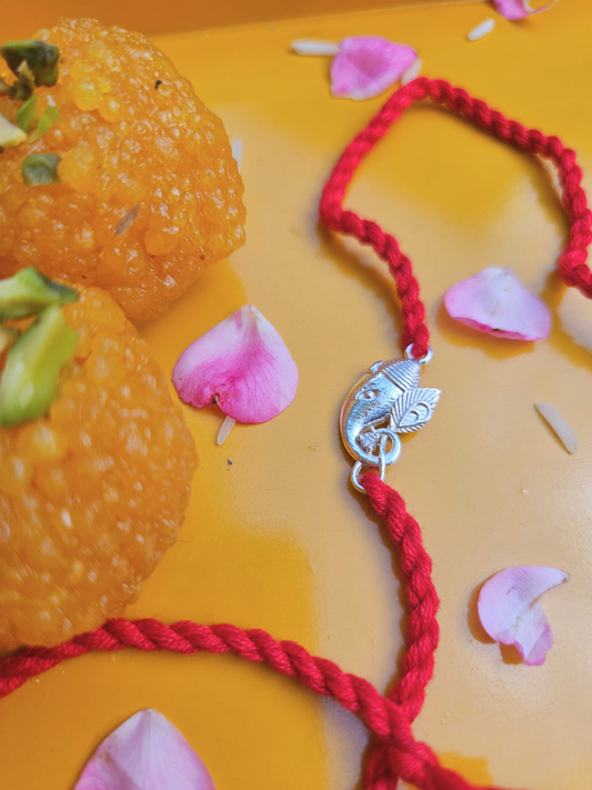 Ganesha rakhi with laddu and rose petals for Raksha Bandhan